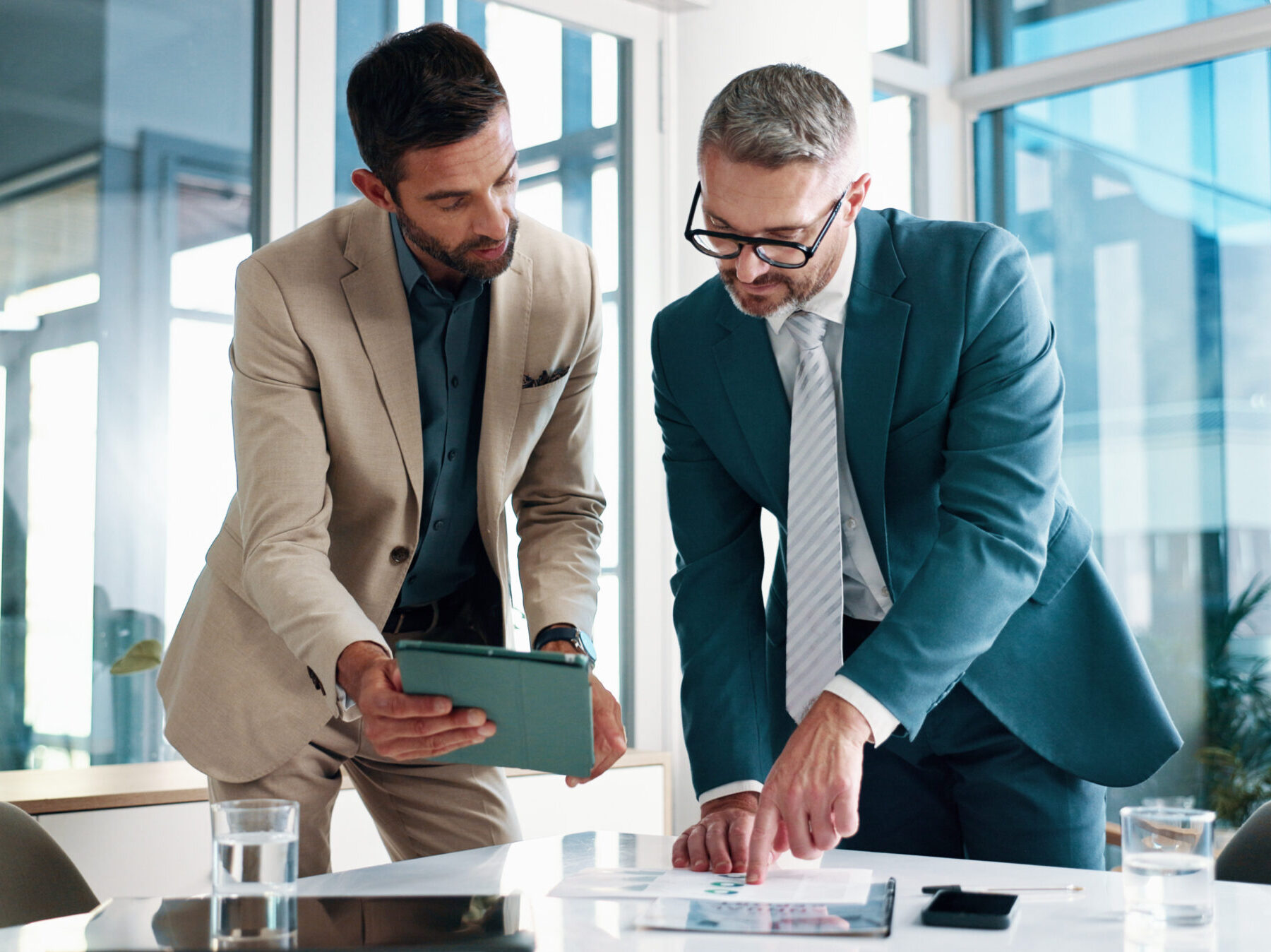 Business, people and meeting on tablet at office of planning, financial documents and company growth. Men, collaboration and paperwork with profit graph, investment report and feedback of opportunity